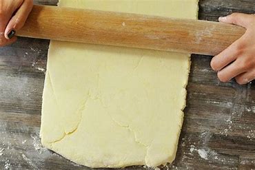 Une pâte feuilleté sans gluten poser sur une table entrain de de faire aplatir avec un rouleau pâtisser.